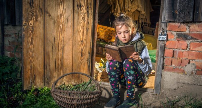 A girl reads a book in the barn