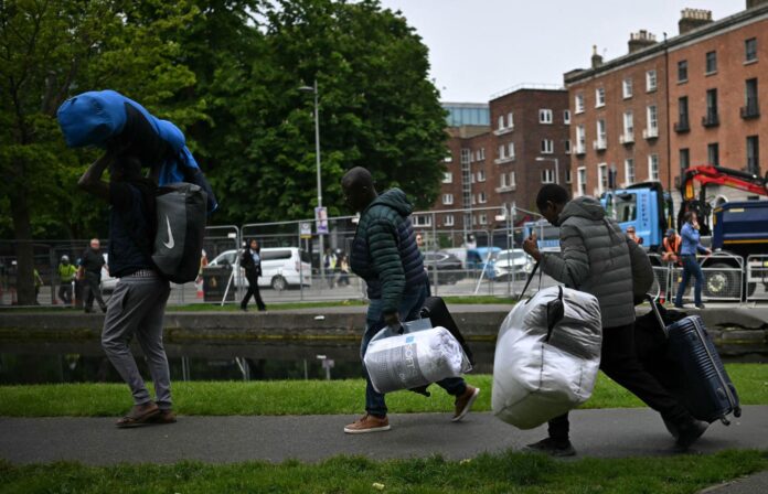 avrupa-gocmenler 21 Mayıs 2024'te Avrupa İrlanda'da Dublin'in batısındaki Büyük Kanal kıyılarında kamp alanı boşaltılırken, göçmenler tarafından kurulan geçici kamptan eşyalarını taşıyan insanlar. (Fotoğraf: BEN STANSALL/AFP, Getty Images aracılığıyla)